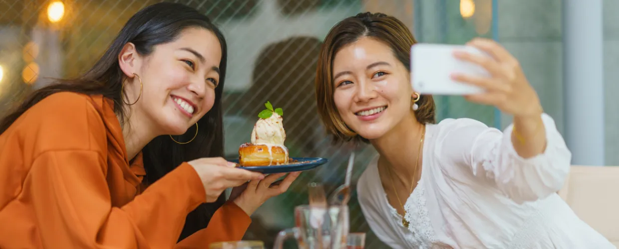 Two women taking a selfie with a dessert.